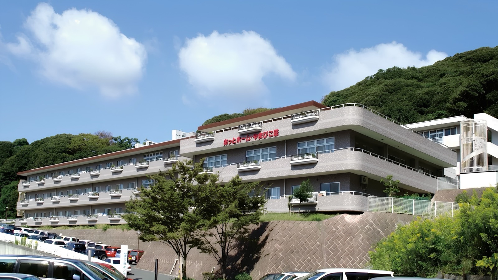 あっとホーム・やまびこ荘の建物外観。山を背に立つ3階建ての施設で、デイサービスはこの建物群内に位置する